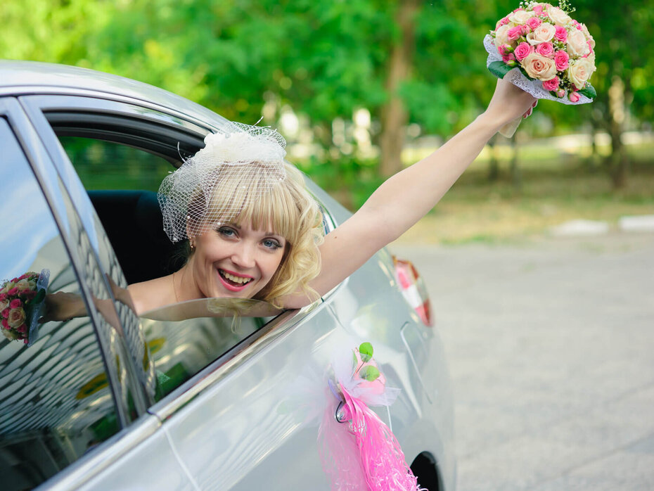 Braut hält Brautstrauß aus dem Hochzeitsauto