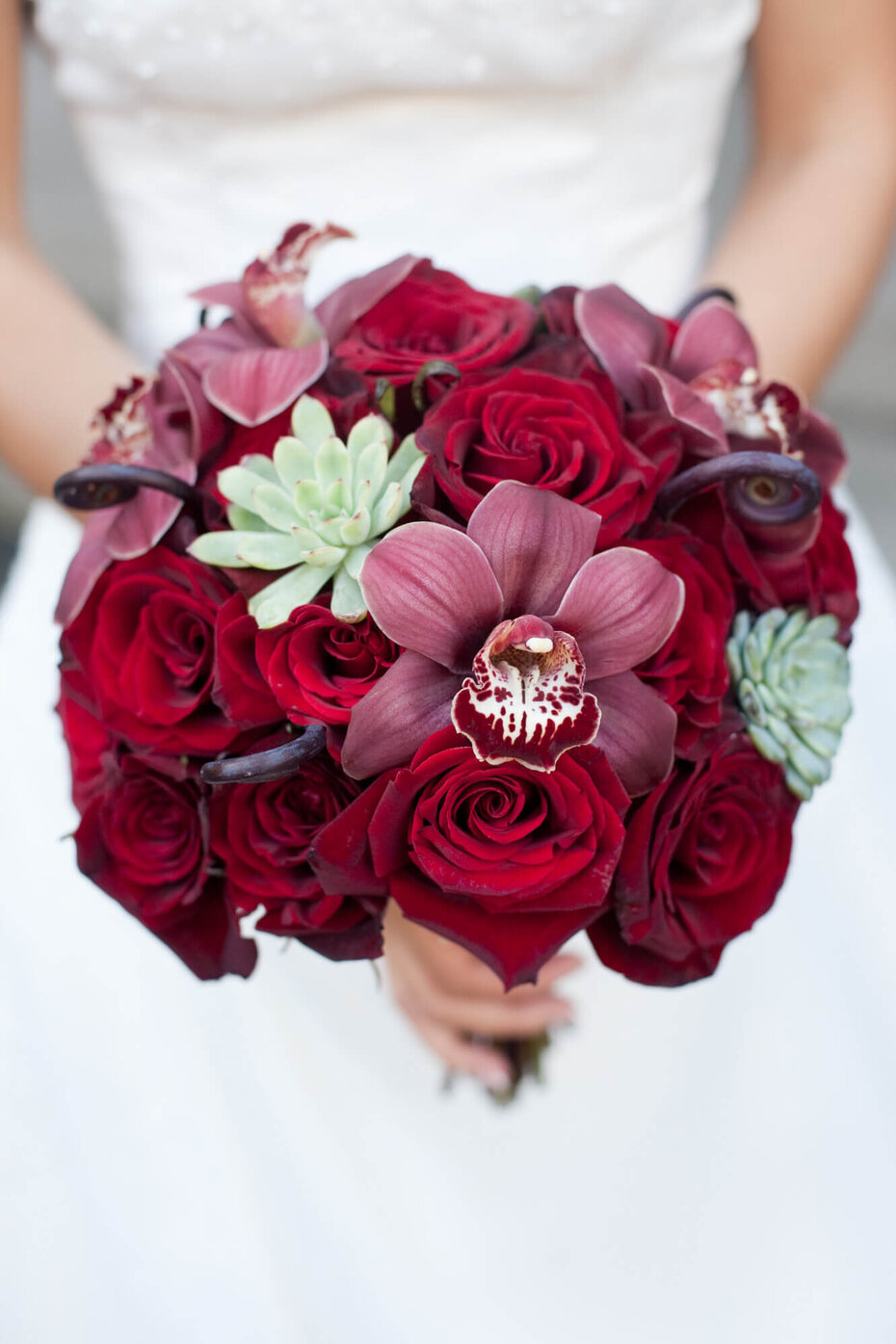 Eine Braut hält ihren Brautstrauß aus roten Rosen