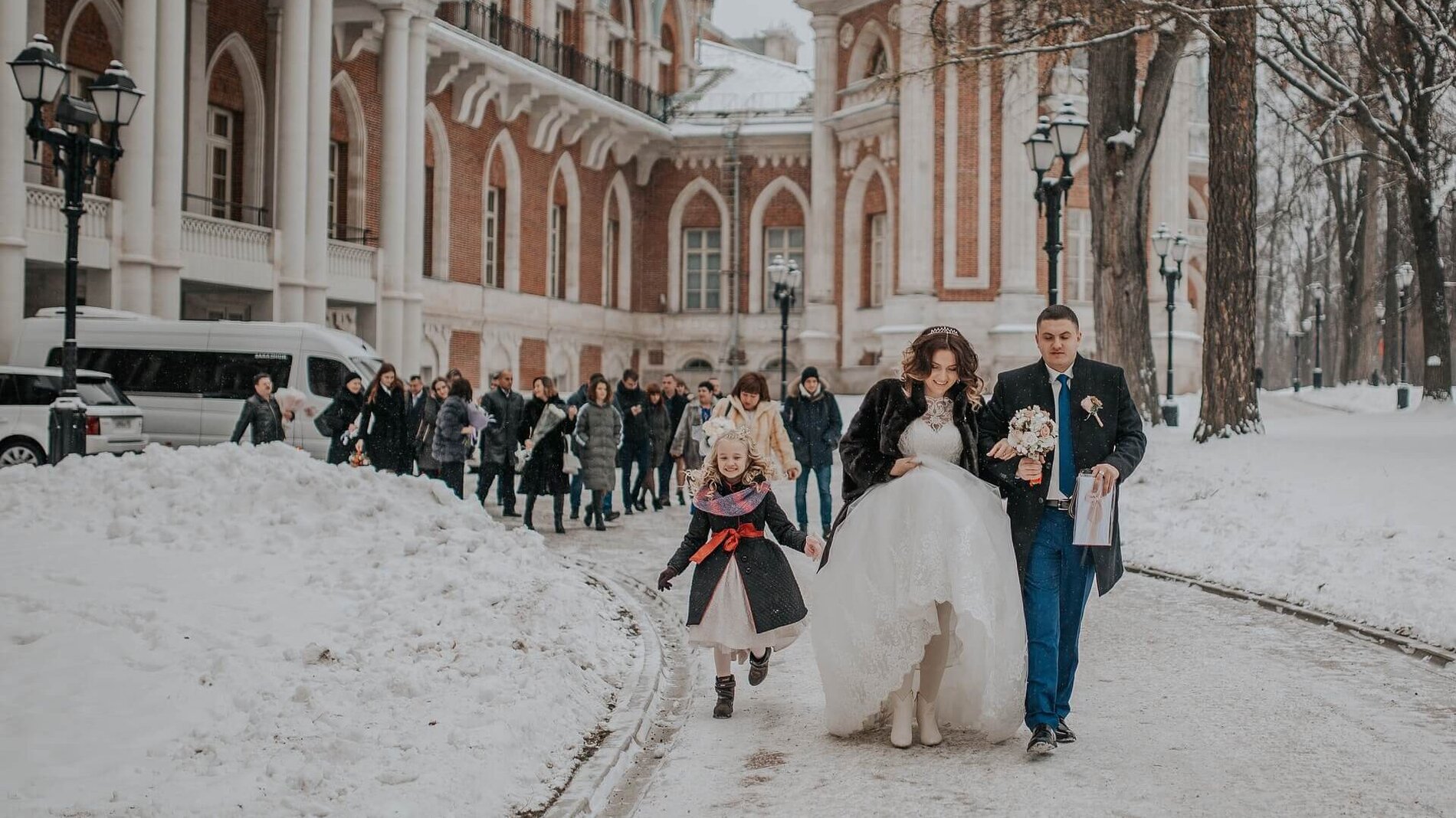 Brautpaar und Hochzeitsgesellschaft laufen im Schnee