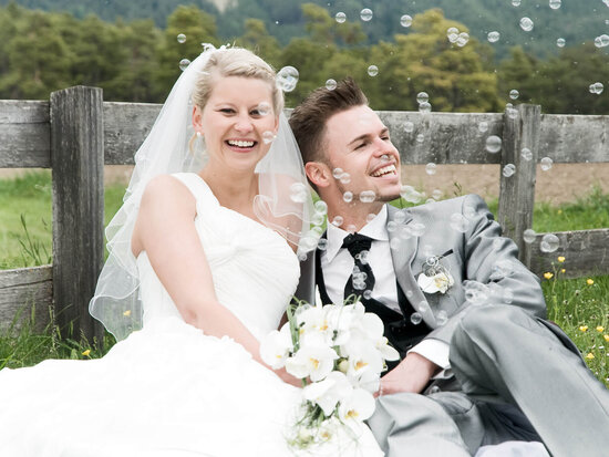 Glückliches Brautpaar sitzt auf einer Wiese