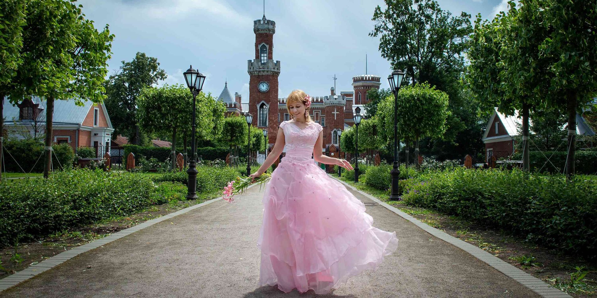 Braut in rosa Brautkleid vor einem Schloss