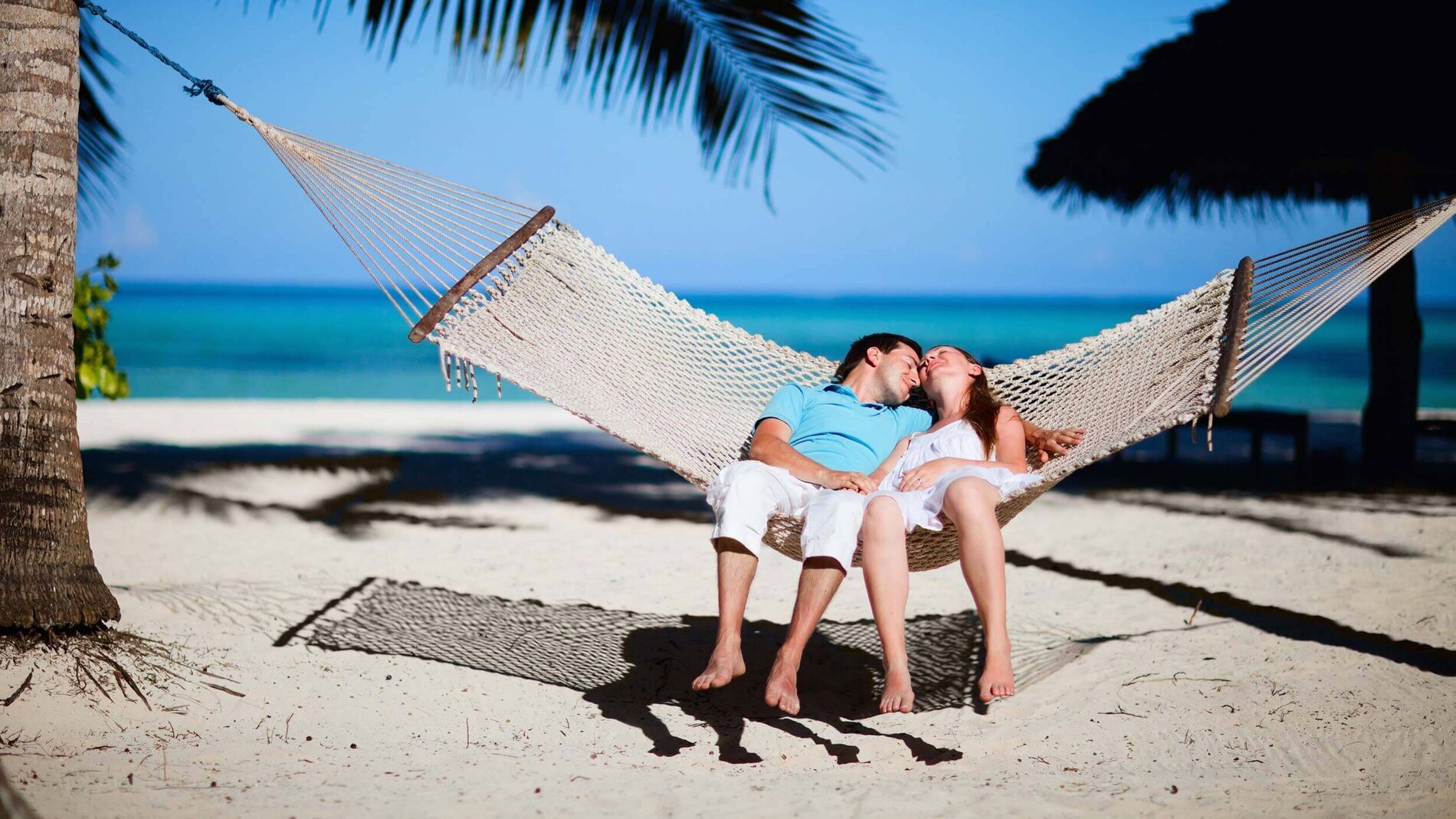 Ein Brautpaar liegt in einer Hängematte am Strand