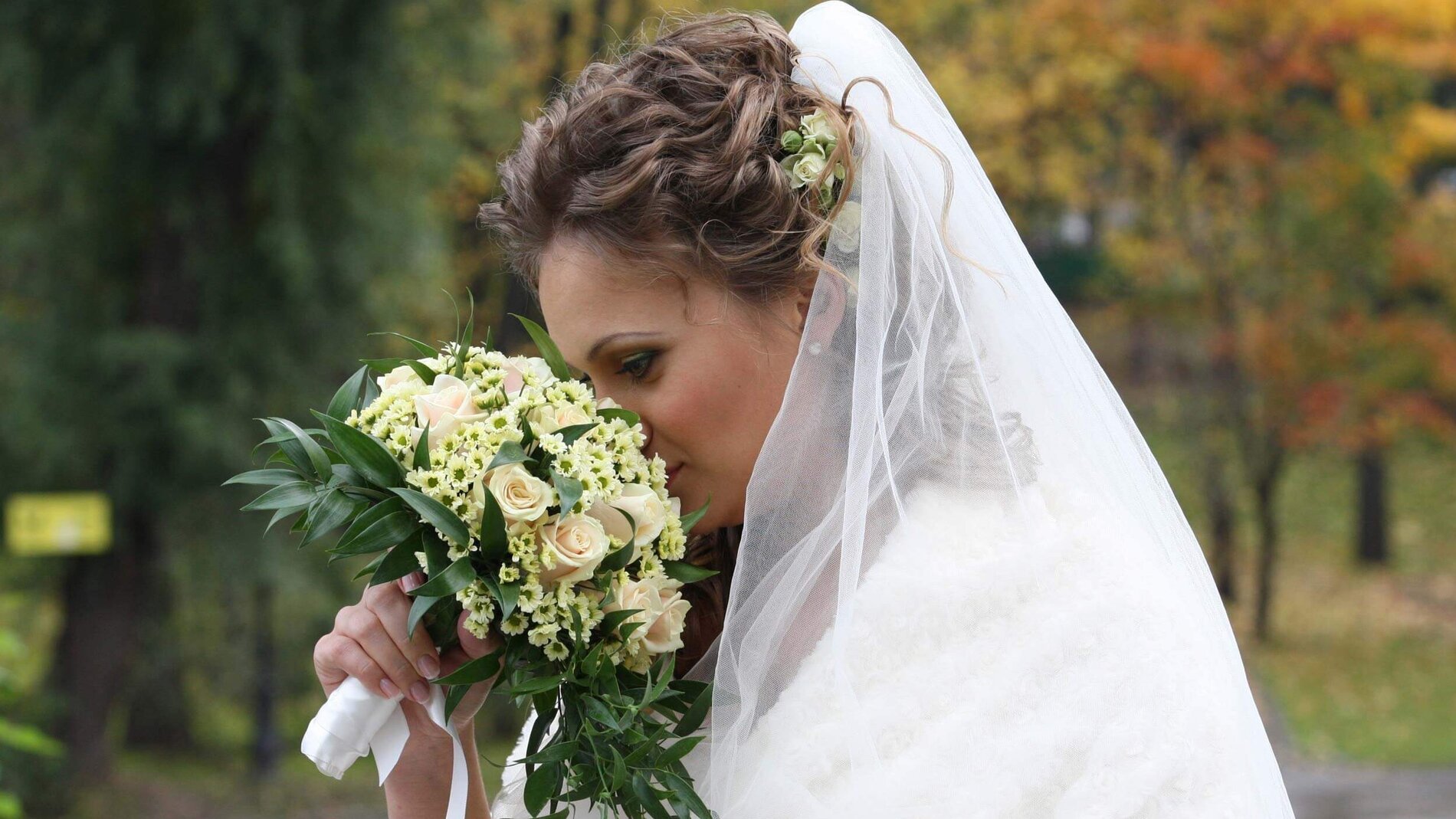 Braut riecht an den Blumen ihres Brautstraußes
