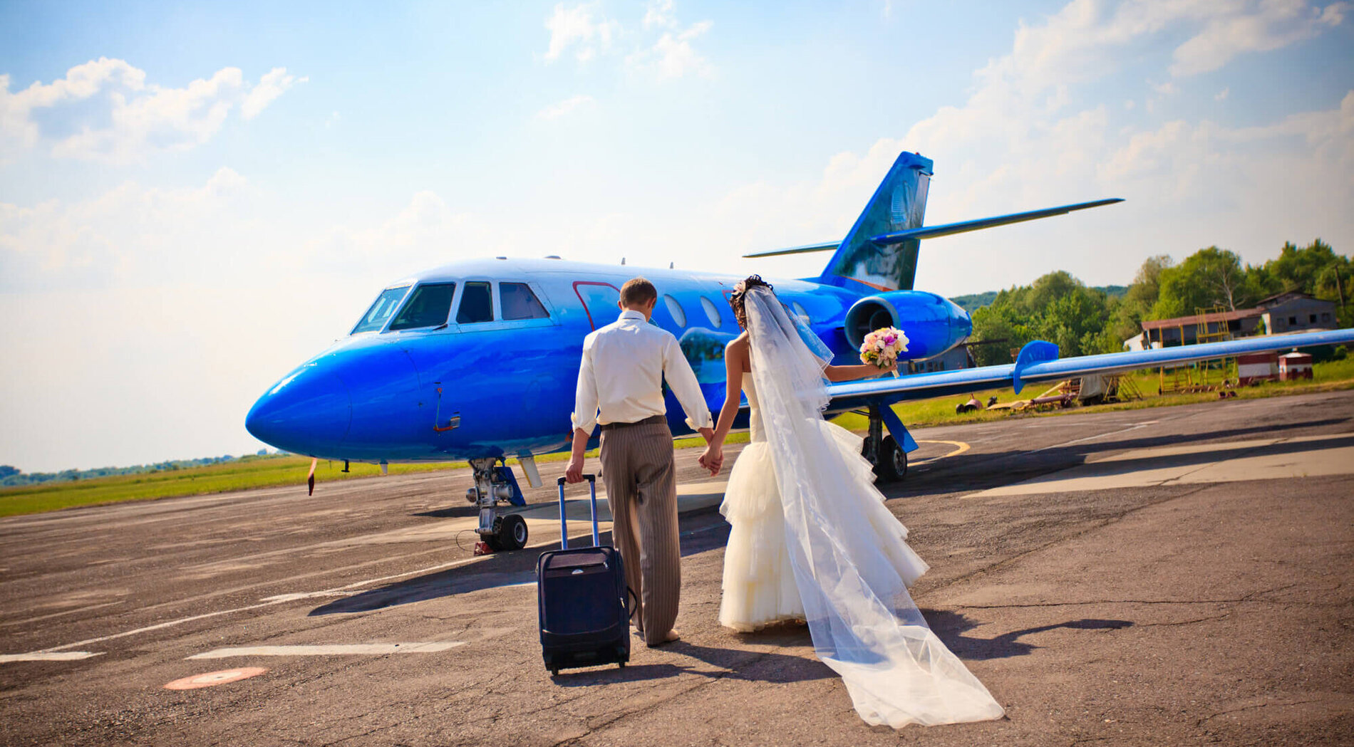 Brautpaar auf dem Weg zum Flugzeug in die Flitterwochen