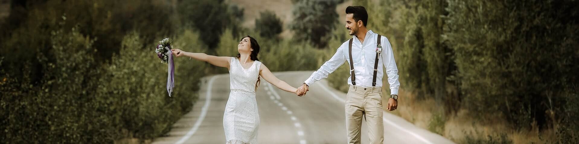 Ein glückliches Brautpaar läuft auf einer Straße und hält sich die Hände