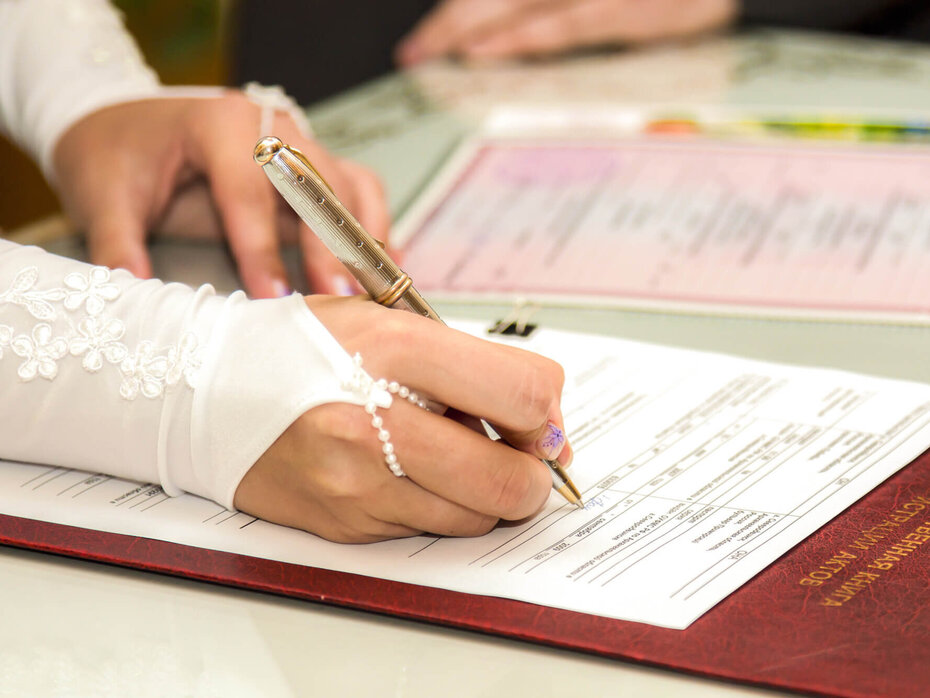 Braut unterschreibt Dokumente beim Standesamt