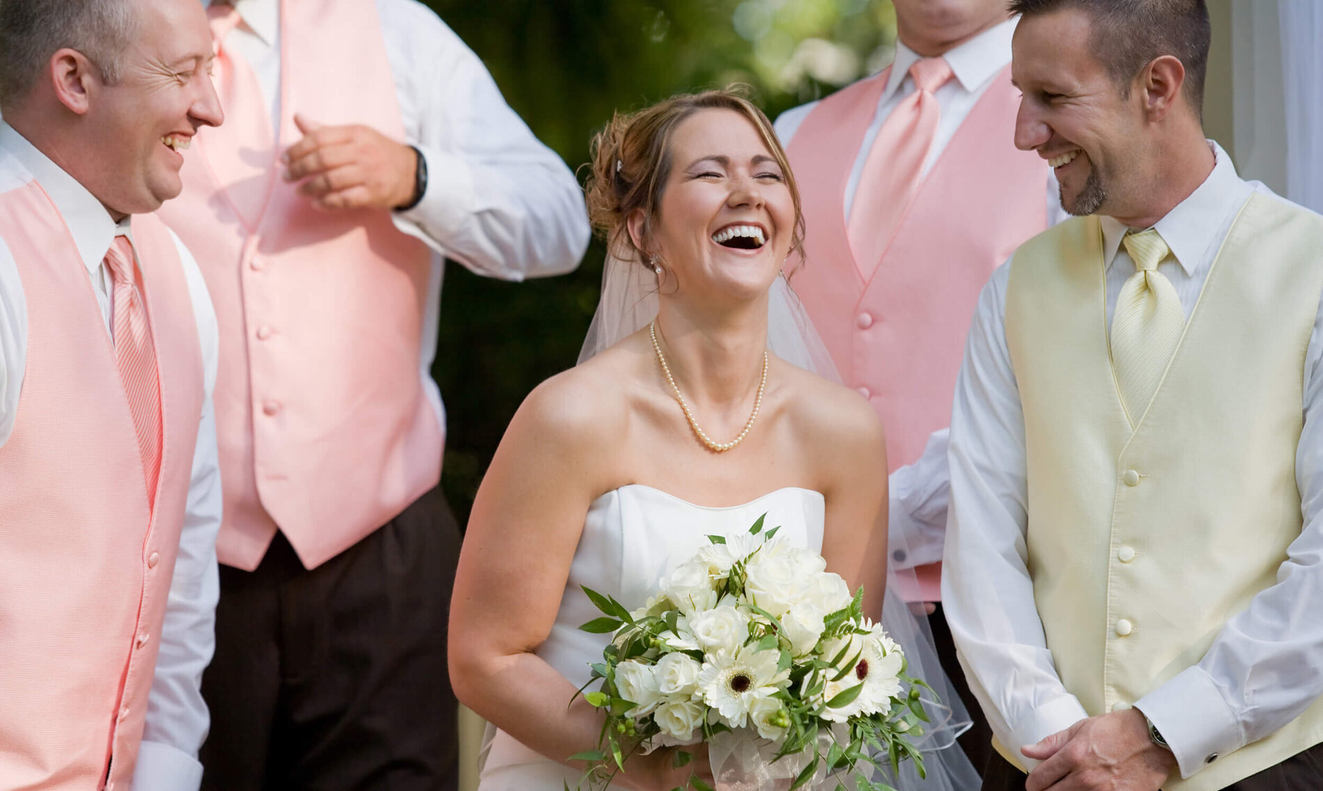 Eine lachende Braut mit Bräutigam und Brautführern