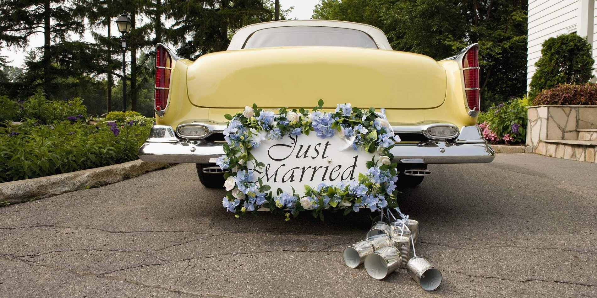 Hochzeitsauto dekoriert mit Schild, Blumen und Blechdosen