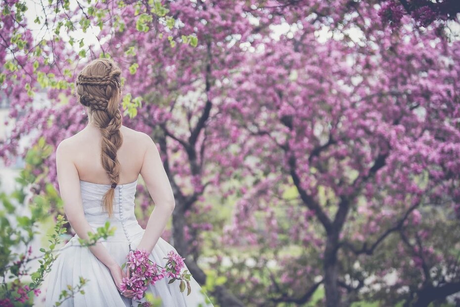 Braut umgeben von violett blühenden Bäumen